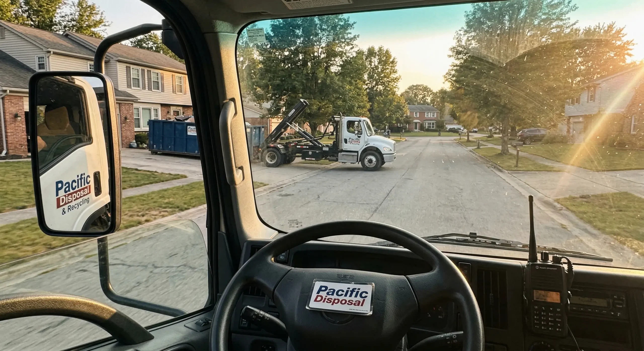 First person view from dumpster truck cab showing dashboard branding during delivery
